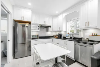 a kitchen with white cabinets and a white table at New laneway house near Airport, World Cup stadium, Downtown, UBC in Vancouver