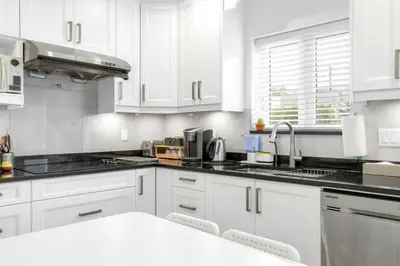 a white kitchen with white cabinets and a sink at New laneway house near Airport, World Cup stadium, Downtown, UBC in Vancouver