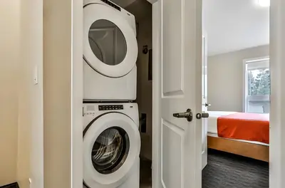 a white washing machine in a room with a bed at Mountain Surrounded Lodge in Harvie Height in Canmore