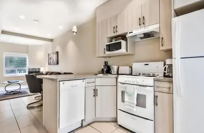 a kitchen with white appliances and a table at Mountain Surrounded Lodge in Harvie Height in Canmore