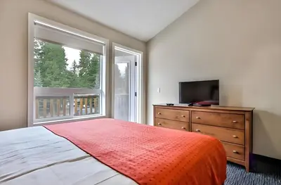a bedroom with a bed and a television and a dresser at Mountain Surrounded Lodge in Harvie Height in Canmore