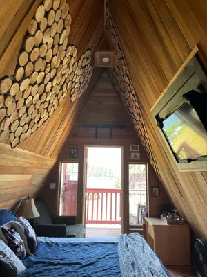 a bedroom with a bed in a room with wooden ceilings at Bratty Catty Cabin in Powell River