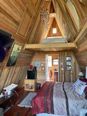 a bedroom with a bed in a wooden cabin at Bratty Catty Cabin in Powell River
