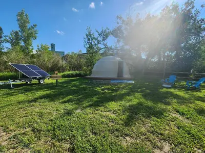 a tent and a solar panel in a yard at D3 Rainforest Getaway Dome- 2Dbl beds in Drumheller