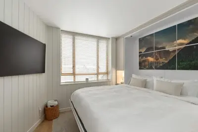a bedroom with a large white bed and a large window at KING Bed - Premium STUDIO Suite - Ski Valet - Village in Whistler