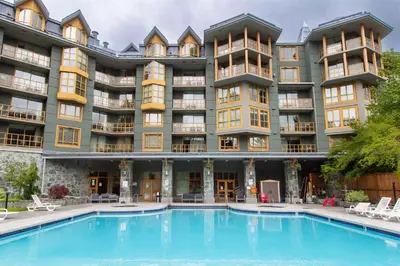 a large apartment building with a swimming pool at KING Bed - Premium STUDIO Suite - Ski Valet - Village in Whistler