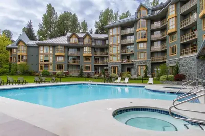 a large apartment building with a large swimming pool at KING Bed - Premium STUDIO Suite - Ski Valet - Village in Whistler