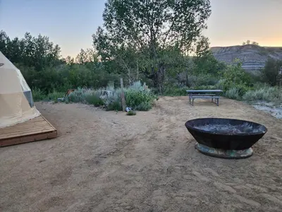 a field with a tent and a fire pit and a bench at D6 Sahara Sunset- King Suite Very Private in Drumheller