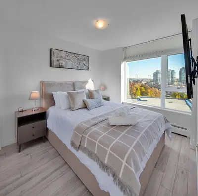 a white bedroom with a large bed with a window at Stylish 2BD Condo in Downtown with Marina View in Vancouver
