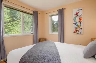 a bedroom with a bed and two windows at 4BR in Blueberry Hill Estates, Mountain Views, Large Family Home, Wood Fireplace, Balcony in Whistler