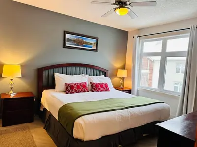 a bedroom with a bed with red pillows and a window at W463 Canmore 2BD 2BT, AC, MT view, Central Location in Canmore