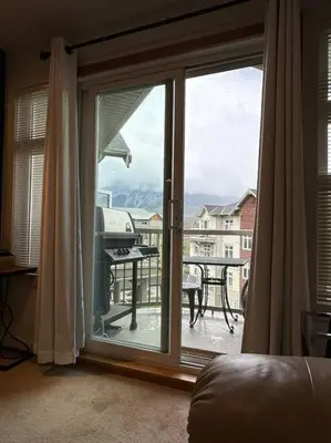 a room with a sliding glass door with a view of a balcony at W463 Canmore 2BD 2BT, AC, MT view, Central Location in Canmore