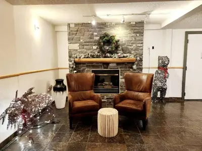 a living room with two chairs and a fireplace at W463 Canmore 2BD 2BT, AC, MT view, Central Location in Canmore