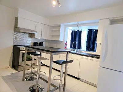 a kitchen with a black counter and stools in it at Lovely Cozy Room! with Attached Private Bath in the Heart of Vancouver! Private Parking & Self Check-in! in Vancouver