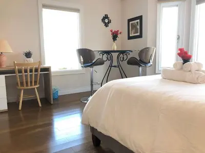a bedroom with a bed and a table and chairs at Heated pool, hot tub, 4 AC lake view bedrooms in West Kelowna