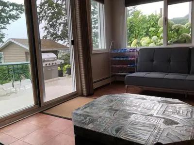 a living room with a couch and large windows at Heated pool, hot tub, 4 AC lake view bedrooms in West Kelowna