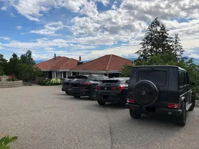 a row of cars parked in front of a house at Heated pool, hot tub, 4 AC lake view bedrooms in West Kelowna