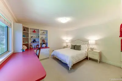 a bedroom with a white bed and a red desk at Beautiful Dunbar Home in Vancouver