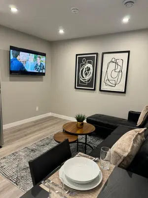 a living room with a couch and a tv on the wall at Private Modern Retreat in the NW - 12 mins to Airport - Near Shops - Easy Banff Access in Calgary