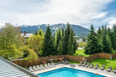 a backyard with a swimming pool and chairs and mountains at a fully renovated condo near village centre with MT view and close to lift in Cascade lodge in Whistler