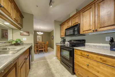 a kitchen with wooden cabinets and a stove top oven at The Peaks 3 Bedroom Mountain View Condo in Radium Hot Springs