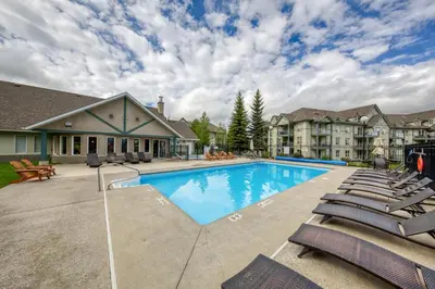 a swimming pool with lounge chairs in front of a building at The Peaks 3 Bedroom Mountain View Condo in Radium Hot Springs