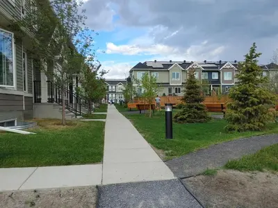 a sidewalk in a park with benches and houses at Genesis Townhouse in Calgary