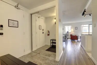 an open living room with white walls and wooden floors at Stylish DT Views at Stampede w Free Parking and AC in Calgary