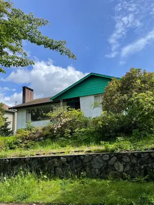 a house with a green roof and a stone wall at Green House in Vancouver West in Vancouver