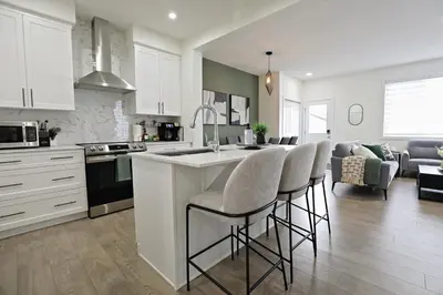 a kitchen with white cabinets and a kitchen island with bar stools at Elegant Retreat with King Beds,Golf,Disney,Near WEM in Edmonton