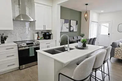 a kitchen with white cabinets and a kitchen island with a sink at Elegant Retreat with King Beds,Golf,Disney,Near WEM in Edmonton