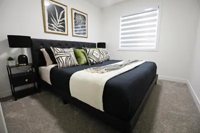 a bedroom with a black bed with pillows and a window at Elegant Retreat with King Beds,Golf,Disney,Near WEM in Edmonton