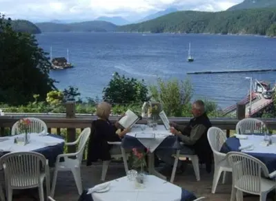 two people sitting at tables with a view of the water at Shannaghs Sweet Escape in Powell River