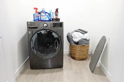 a washing machine sitting next to a laundry basket at Elegant Escape with King Bed, Long Stays, WEM, Disney in Edmonton