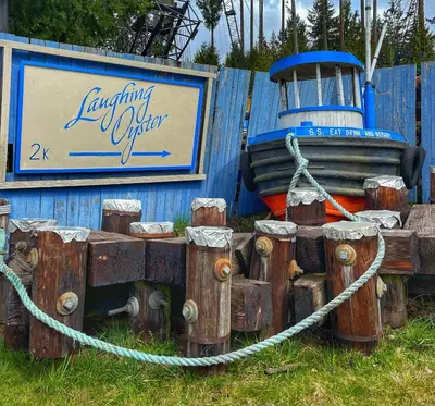 a wooden boat sitting next to a blue fence at Gracies Grotto Cabin in Powell River