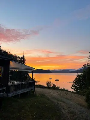 a cabin with a view of a lake at sunset at Gracies Grotto Cabin in Powell River