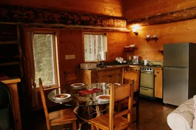 a kitchen with a table with chairs and a refrigerator at Rustic Dream Cabin at Beaverfoot in Parson