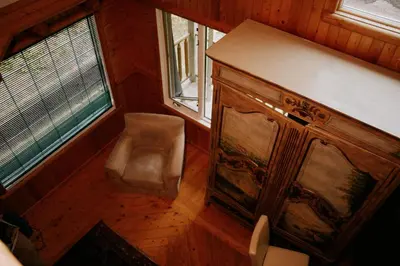 a room with a chair and a cabinet and two windows at Rustic Executive Cabin at Beaverfoot in Parson