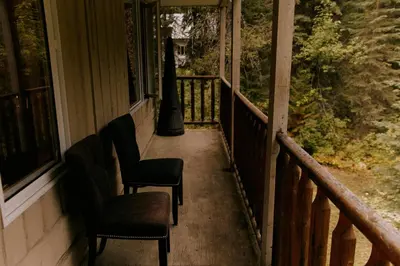 a porch with two chairs and a light pole at Rustic Executive Cabin at Beaverfoot in Parson