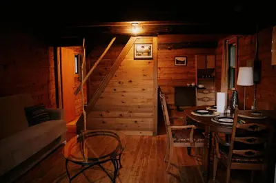 a dining room with a table and a staircase at Rustic Woodland Cabin at Beaverfoot in Parson