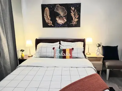 a bedroom with a bed and two lamps and a chair at Spacious & Comfy Upper Floor 3BR Suite in Detached House in Calgary