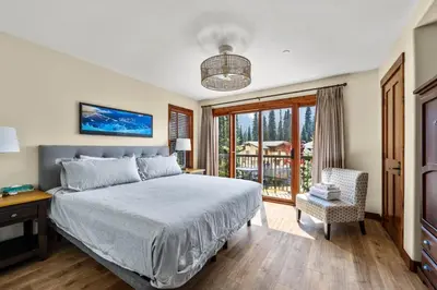 a bedroom with a bed and a balcony at Trappers Landing #30 townhouse in Sun Peaks
