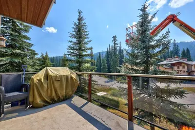 a balcony with a table and a chair and trees at Trappers Landing #30 townhouse in Sun Peaks