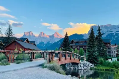 a bridge over a river with mountains in the background at #304 Mountain View 1BR in Canmore DT in Canmore