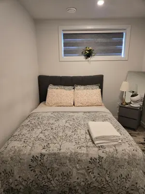 a bedroom with a bed with a blanket and a window at Parkside Basement Suite in Edmonton