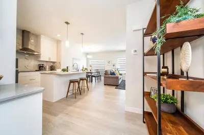 a kitchen and living room with white cabinets and a table at Beautiful Elegant Home Sleeps 10, Free Parking, Central AC in Edmonton