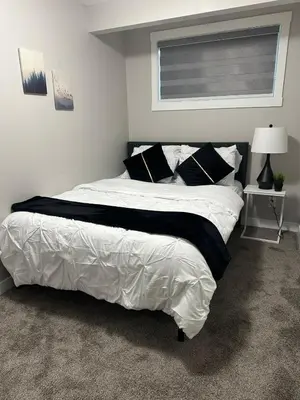 a bedroom with a large white bed with black pillows at Luxurious Home in NW Calgary, Free Parking, High Speed Internet, Near Grocery and Airport in Calgary