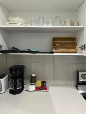 a kitchen shelf with dishes and a coffee maker at Luxurious Home in NW Calgary, Free Parking, High Speed Internet, Near Grocery and Airport in Calgary