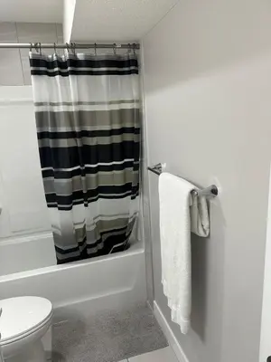 a bathroom with a shower curtain and a toilet at Luxurious Home in NW Calgary, Free Parking, High Speed Internet, Near Grocery and Airport in Calgary