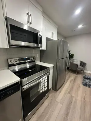 a kitchen with a stove and a stainless steel refrigerator at Luxurious Home in NW Calgary, Free Parking, High Speed Internet, Near Grocery and Airport in Calgary